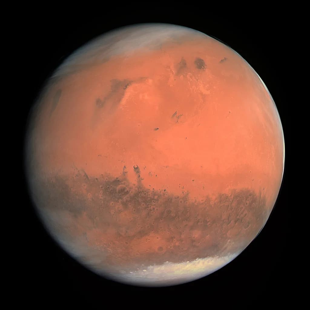 Mars seen as a full disc from orbit — rust-coloured surface with a bright polar ice cap.